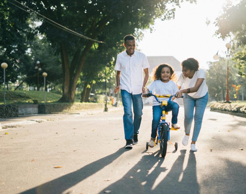 Parents teaching their daughter how to ride a bike